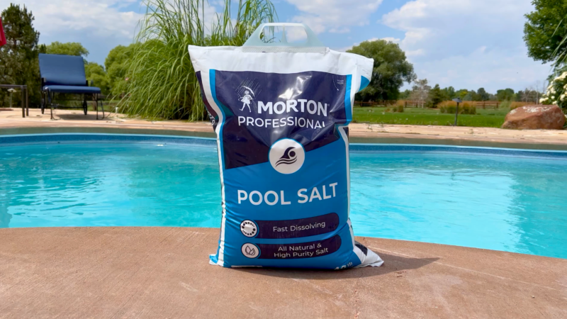 The Best Pool Salt You Should Use And Why 2 A bag of morton professional pool salt next to a saltwater inground pool.