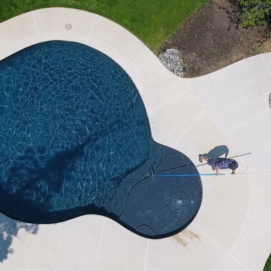 Drone Shot of Man Brushing an Inground Pool