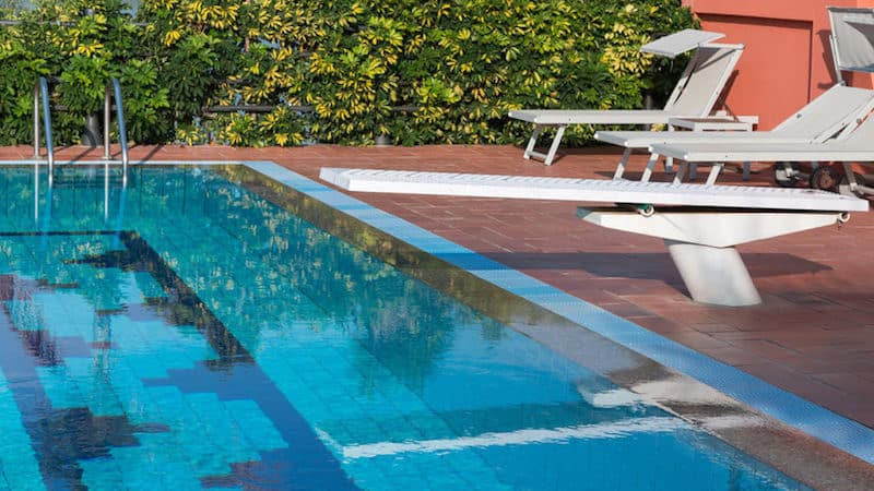 Outdoor pool with springboard and lounge chairs.